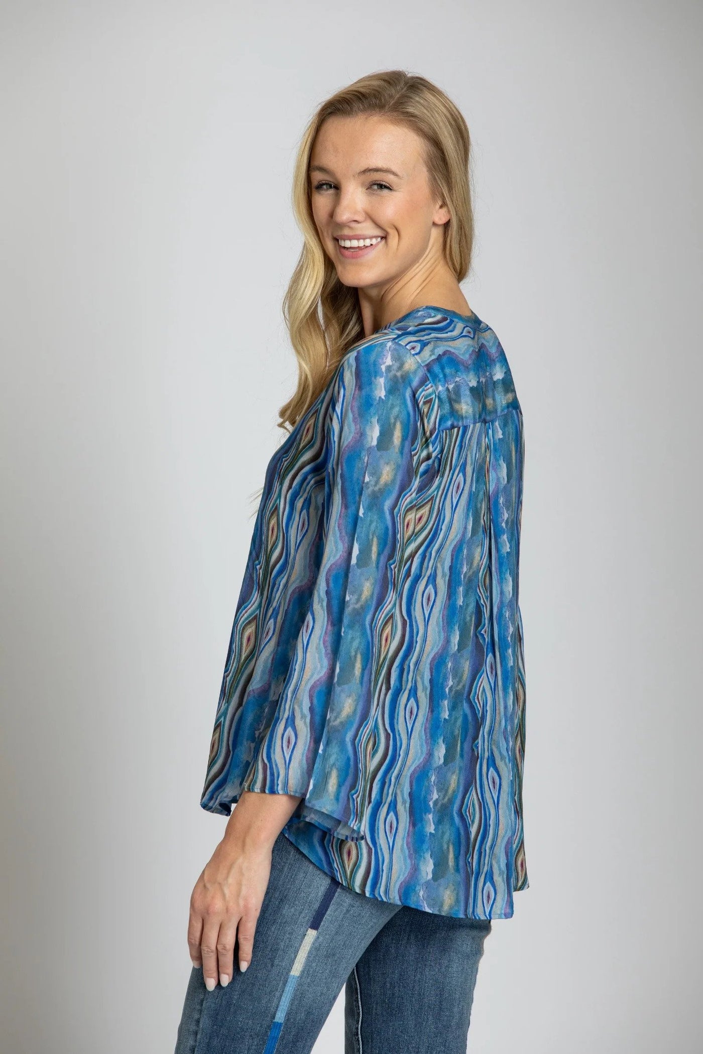 Blue Abalone Inspired Print with Tasseled V-Neck Top Looking Over Shoulder.