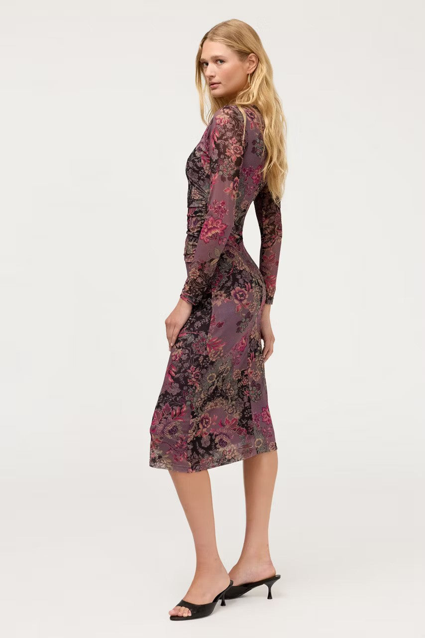 Side view of The Johnny Was Long Sleeve Ruched Front Mesh Midi Dress with a dark floral pattern in purple, pink, and black, paired with black mule heels, against a plain light gray studio background.