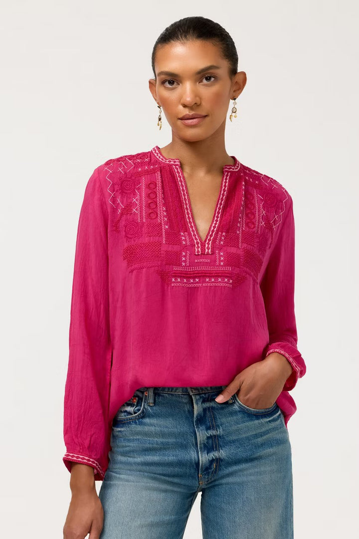 A women wearing Johnny Was Wes Blouse and blue jeans looks at the camera with her left hand in pocket and front hem tucked n her jeans.