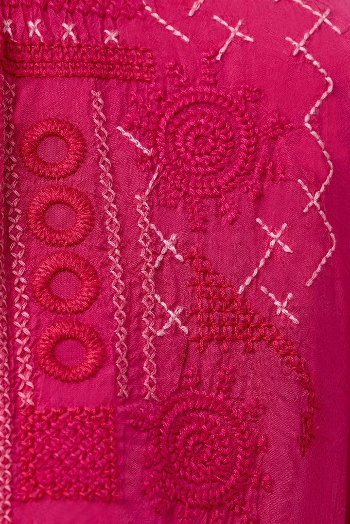A close-up of the exquisite artisan embroidery on The Johnny Was Wes Blouse in Cherries Jubilee. Showcasing detailed hand-stitched patterns including paisley, geometric lines, and circular motifs in matching and contrasting pink and white threads.
