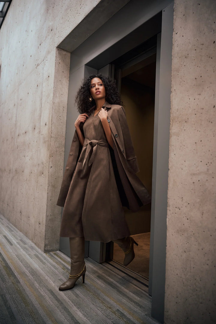 A women walking out of a door wearin Joseph Ribkoff Faux Suede Car Coat draped over her shoulder looking down the street.