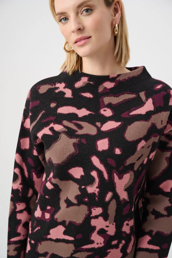 Close-up of woman wearing the Joseph Ribkoff Abstract Print Sweater Style 263930, highlighting the bold abstract print and the delicate, heat-transfer rhinestone accents.