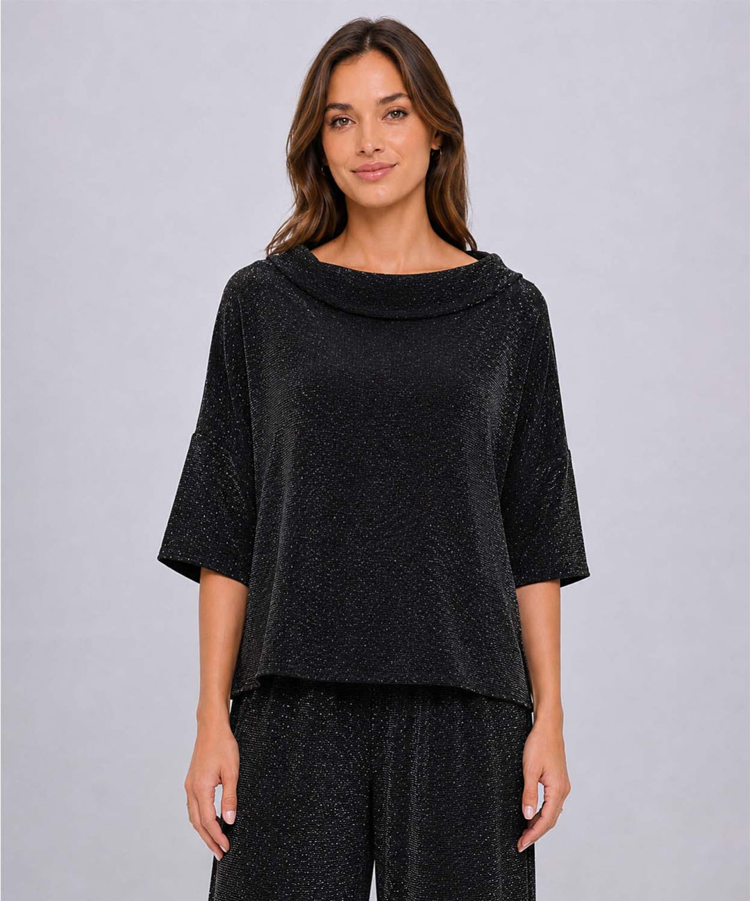 A smiling model wearing a black Last Tango Glitter High-Low Top with a boat neck and 3/4 sleeves and beautiful sparkles. 