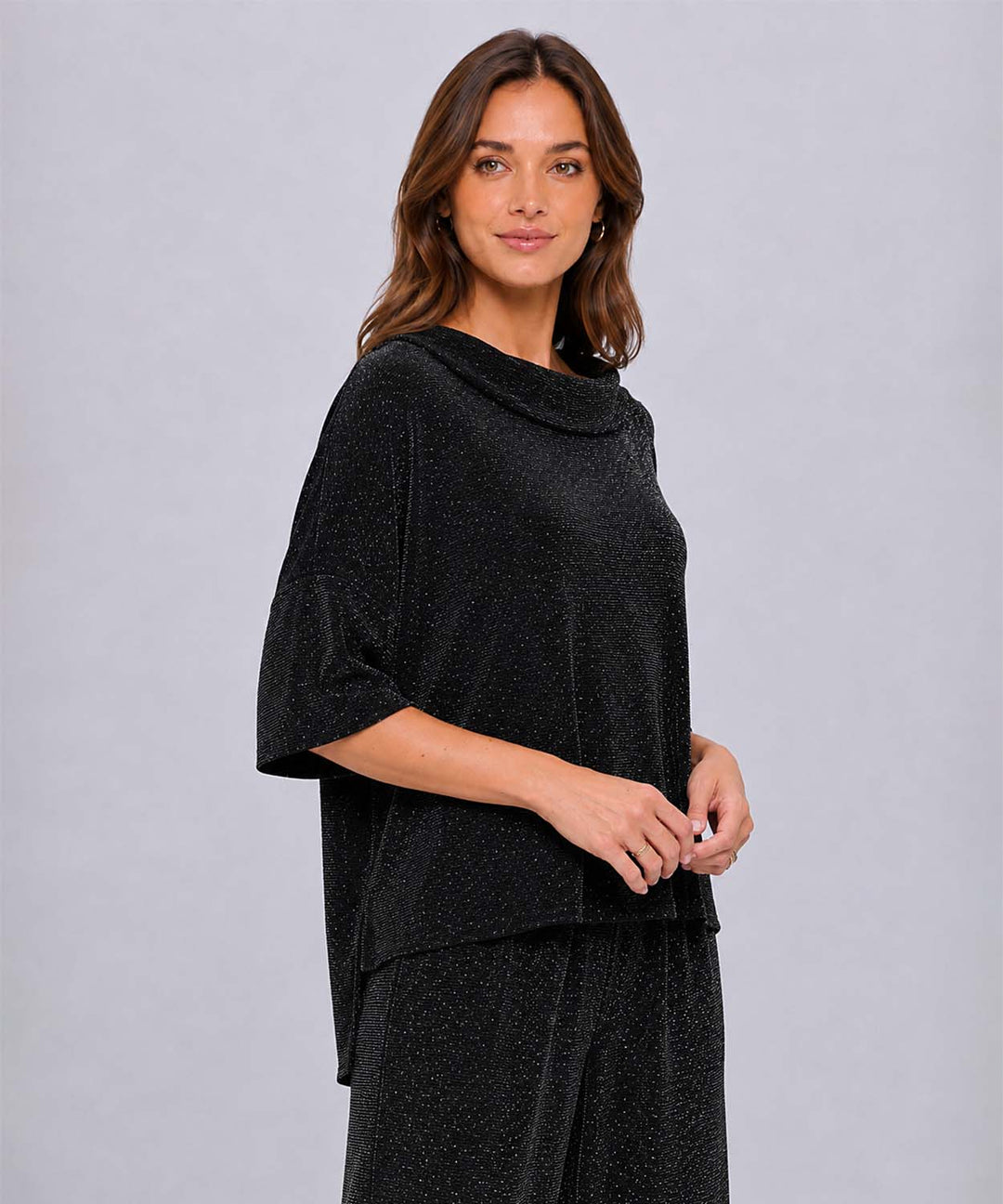 A side view of a women wearing a black Last Tango Glitter High-Low Top with a boat neck and 3/4 sleeves and glimering sparkles.